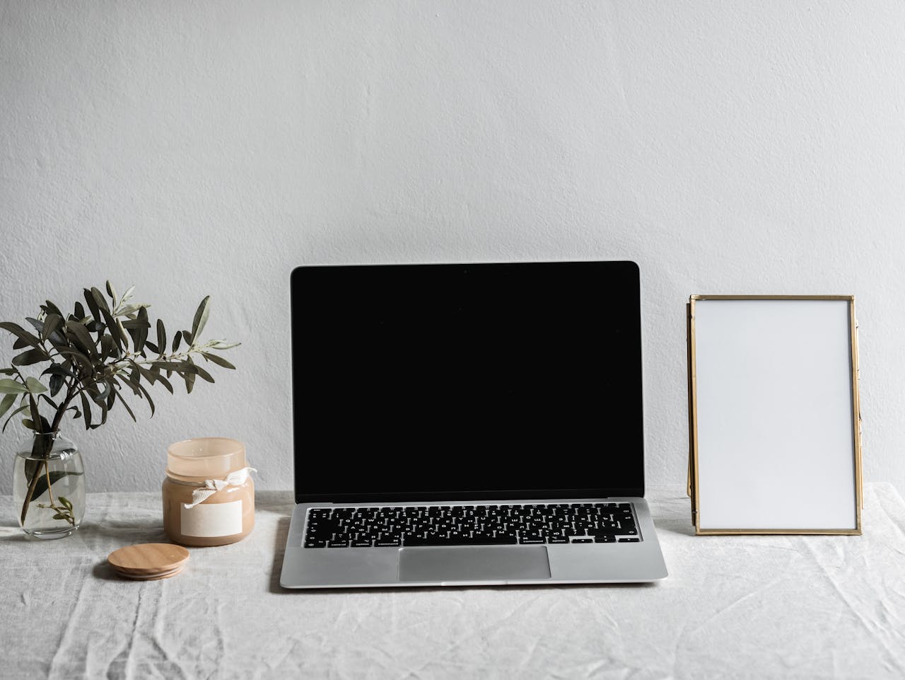 Services-02 A sleek modern workspace featuring a laptop, candle, vase, and empty frame on a table.